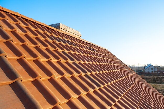 Rangées superposées de tuiles en céramique jaune montées sur des planches de bois couvrant le toit d'un immeuble résidentiel en construction.